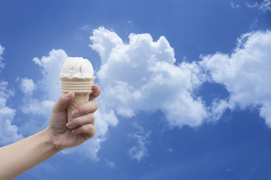 a woman hand holding Ice cream cone with summer blue sky and clouds in background,colorful picture style