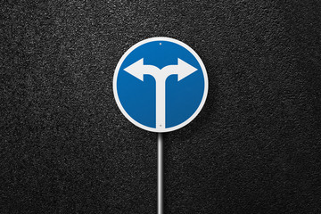 Road sign of the circular shape with pointer on a background of asphalt. Detour. The texture of the tarmac, top view.