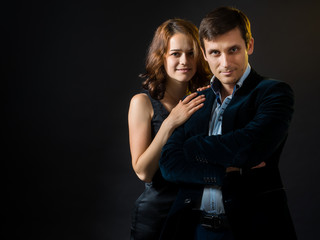 The girl in black skin-tight dress hugging a guy in  velvet jacket