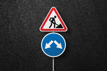 Road signs of the circular and triangular shape with a picture of a worker on a background of asphalt. Pointer. The texture of the tarmac, top view.