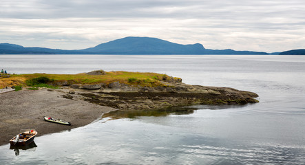 Uninhabited island in the Pacific Northwest US. Two small boats are pulled up on the beach.
