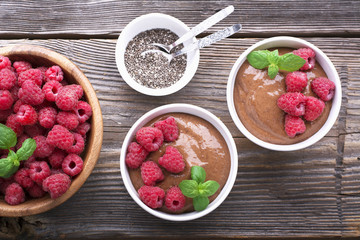 Chocolate Banana Smoothies served fresh juicy ripe raspberries with a sprig of mint in portioned bowls
