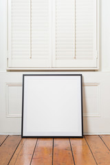 Black picture frame sitting on wooden floor