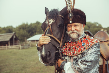 King dressed in medieval costume is stroking his horse 