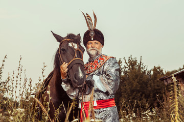King dressed in medieval costume is stroking his horse 