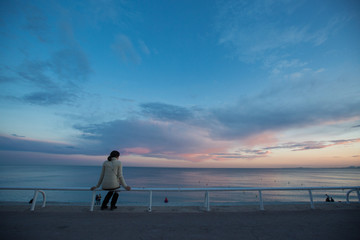 Woman sitting and looking at the sea at evening