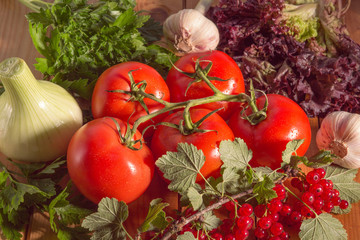 vegetables lying on wooden surface. branch of tomatoes and assorted vegetables