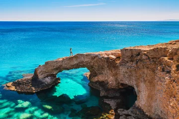 Washable wall murals Cyprus Woman on the beautiful natural rock arch near of Ayia Napa, Cavo Greco and Protaras on Cyprus island, Mediterranean Sea. Legendary bridge lovers. Amazing blue green sea and sunny day.