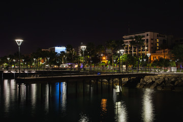 Fototapeta na wymiar Night panorama from coast in Limassol, Cyprus island, Mediterranean Sea. Buildings with reflection in water surface