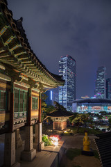 Naklejka premium Ornate building at the Bongeunsa Temple and view of Gangnam in Seoul, South Korea at night.