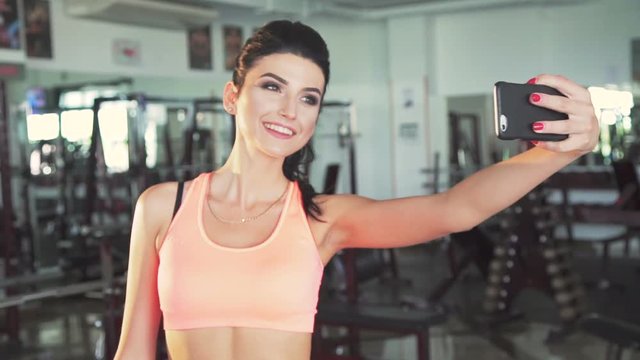 Smart girl taking funny selfies in a modern gym