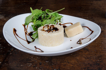 Risotto ai formaggi in primo piano su piatto con rucola e aceto balsamico