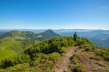 Hiker standing on mountain pass looks at the  mountain tops