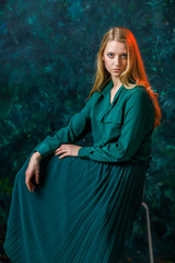 blonde girl on a green background in a long green dress