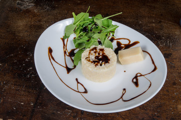 Risotto ai formaggi in primo piano su piatto con rucola e aceto balsamico
