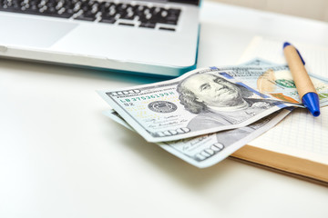Close-up banknote on a notepad with a pen. Screen laptop computer. Freelance desktop with money and notepad.