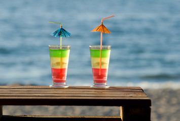 Multi-colored cocktails on a wooden table in the background on the beach and sea