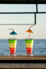 Two cocktails at the bar in the background of the beach and sea