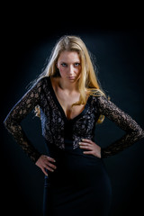 blonde girl on a black background in a dark guipure dress