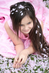 Obraz na płótnie Canvas Little girl on green grass with petals