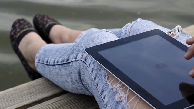 Woman uses digital tablet on a background of the river