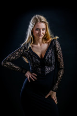 Fototapeta na wymiar blonde girl on a black background in a dark guipure dress