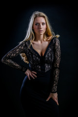 blonde girl on a black background in a dark guipure dress