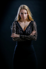 blonde girl on a black background in a dark guipure dress