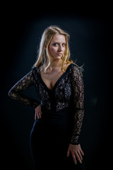 blonde girl on a black background in a dark guipure dress