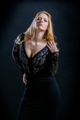Fototapeta na wymiar blonde girl on a black background in a dark guipure dress