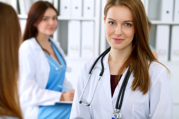 Young beautiful female doctor smiling to patient while consulting her.