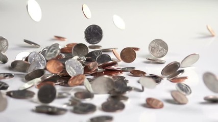 Coins fall onto fall and bounce onto a white surface in slow motion. - Powered by Adobe