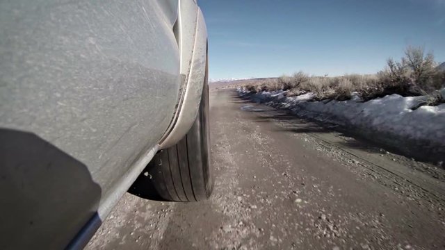 A truck driving fast on a rough and bumpy dirt road.