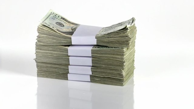 A big stack of money is dropped onto a white surface.