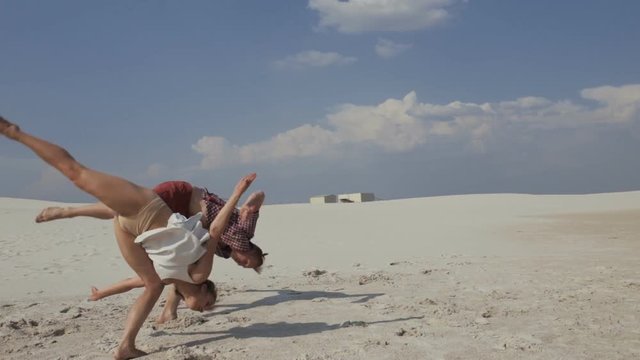 Two dancers doing pair flip in desert