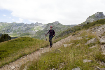 Fototapeta premium happy girl hiking the mountains in Pyrenees, France with her hiking sticks