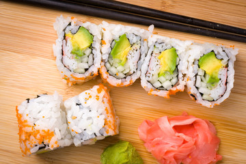 Sushi California rolls appetizer with rice avocado with chopsticks