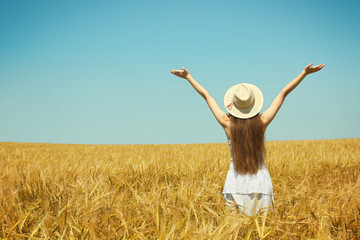 Young woman enjoying nature and sunlight in wheat field