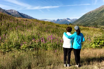 Crédence de cuisine en verre imprimé Denali Mother and daughter looking at wild flowers with mountains 