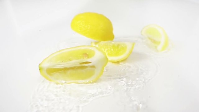 lemon fall splashing on water breaking in four slices slow motion white background