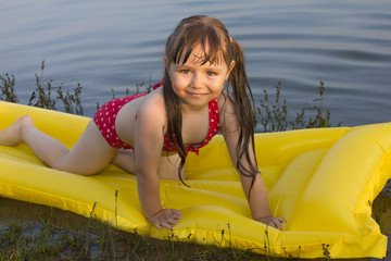little white girl children posture on inflatable mattress on lak