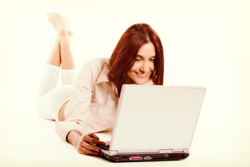 Smiling young woman lying at a floor and she working with laptop