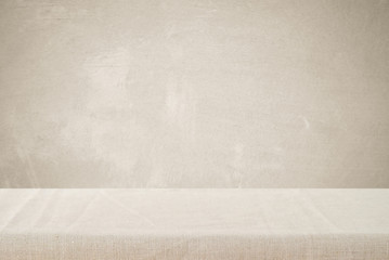 Empty table with linen tablecloth over cement wall background