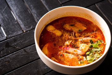 spicy noodle soup on black wooden background