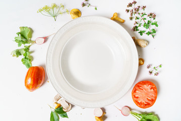 Various vegetables and seasoning cooking ingredients around blank plate