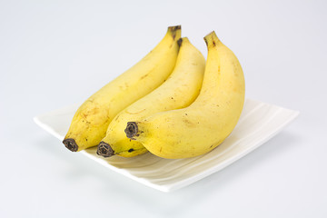 Three of bananas on white plate