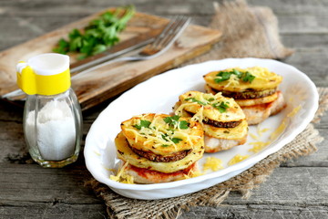Roasted Turkey fillets with potatoes, zucchini, spices, cheese and green parsley. Cutlery on a cutting board, salt shaker, fresh green parsley on a old wooden background. Delicious Turkey meat recipe