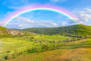 Naklejka premium rainbow over the green hills