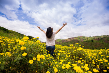 Beautiful Young Woman Outdoors. Enjoy Nature. show hand up with realxing in flower garden in front of the mountain.
