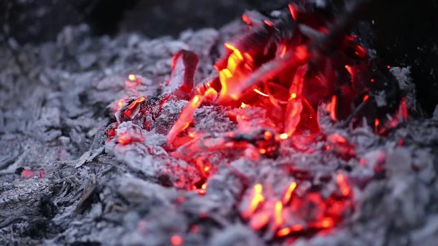 Перемешивание тлеющих углей в сгоревшем костре
